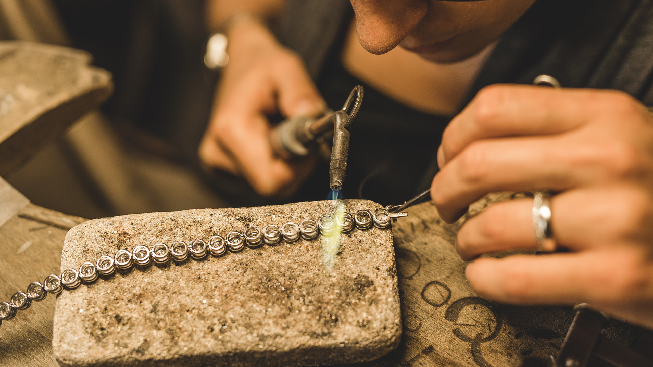 Feine Goldschmiedearbeit mit Flamme an einem Kettenglied.